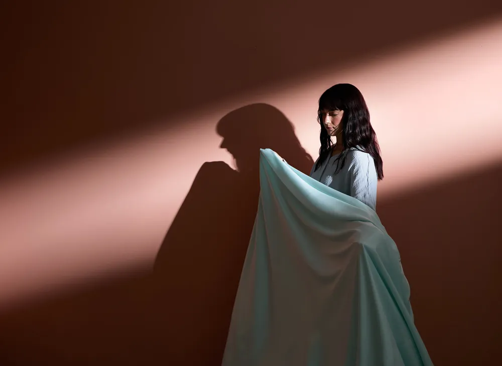 Woman wrapped in a blanket with harsh lighting and shadows